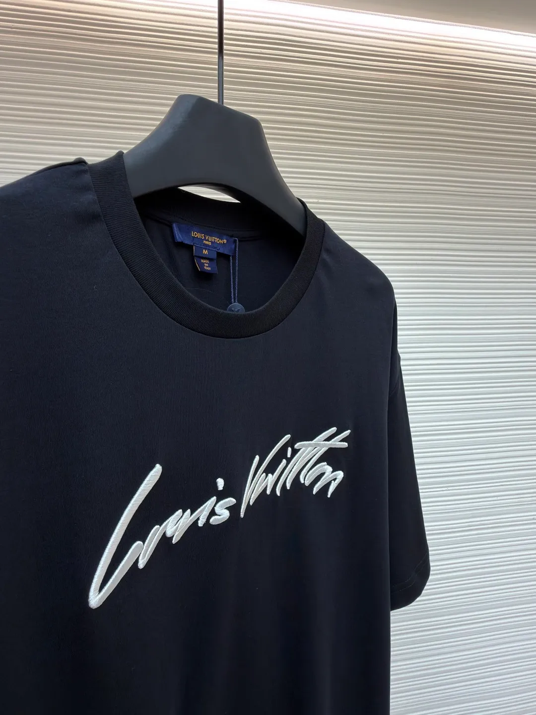 LOUIS VUITTON round neck short sleeves with hand lettering embroidery ●Item number: 1681408-X95 ●Material: long-staple cotton fabric ●Technology: embroidery production ●Color: black ●Version: fitted version ●Weight: about 230 grams ●Size: S-M-L-XL ●Description: Restore 60S single yarn double-sided long-staple cotton, weight 170g; with 32S 1×1 thread, 300g. After being treated with liquid ammonia, it looks like a water-gloss machine. The cloth surface is smooth and has a clear texture, with a slight luster and strong texture. The cotton fiber length of the fabric is long. The advantage of this feature is that after being spun into yarn, the surface of the yarn is smoother, less rough and has a delicate feel. The thin and long features give it a flexible texture, soft skin feel and fabric luster. The front side shows the thickness changes of 3D handwritten font embroidery handwriting strokes and the design pattern after the continuous strokes are simplified; the three-dimensional effect is achieved through multi-layer embroidery threads, filling materials and special stitching methods. Jagged edges are prone to appear on curves and corners; add foam embroidery to the bottom layer of the embroidery and then cut off the excess to form a three-dimensional bulge and improve the smoothness of the lines. Standard H hanging fit with shoulder-length design. The vertical version emphasizes that the width of the shoulders, waist, and hem are basically the same, and it is simple and loose. The short sleeves are tailored to fit the body of the wearer. At the same time, the neckline, cuffs and hem of the short sleeves are all designed with double lines. The overall wiring is straight and delicate, the fabric is comfortable and soft, and the color is consistent without color difference. It can be matched with the same style to create a fashionable look and control various occasions. Customized accessories, complete with three standards, same style for men and women!